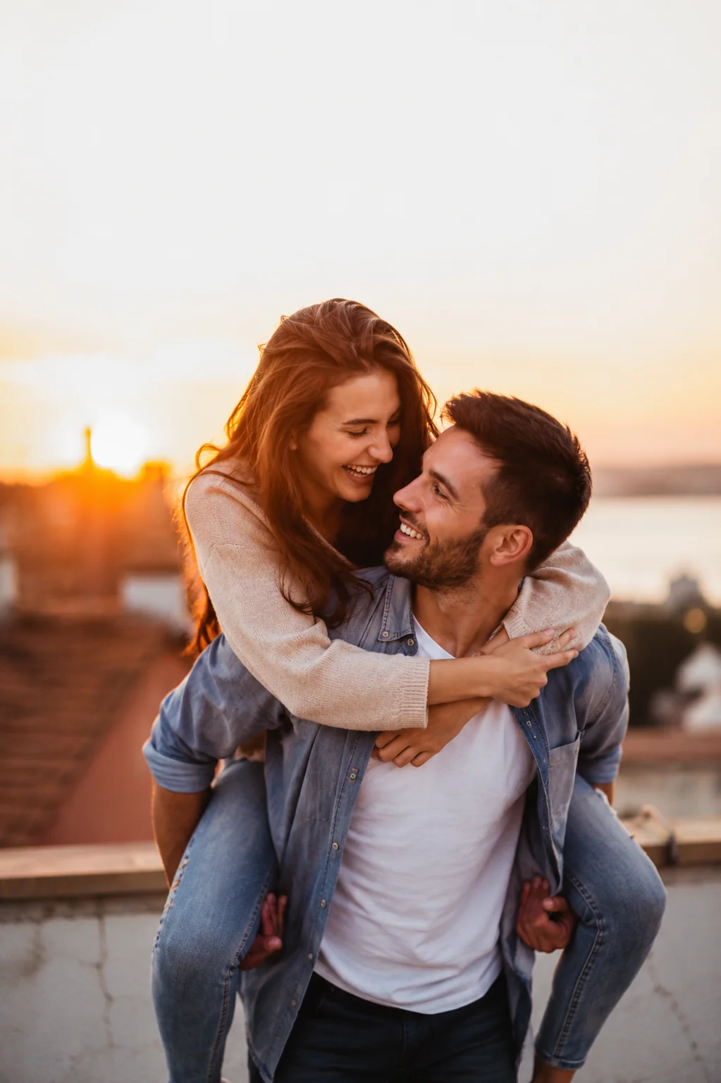 Fun couple sharing a piggyback ride at sunset