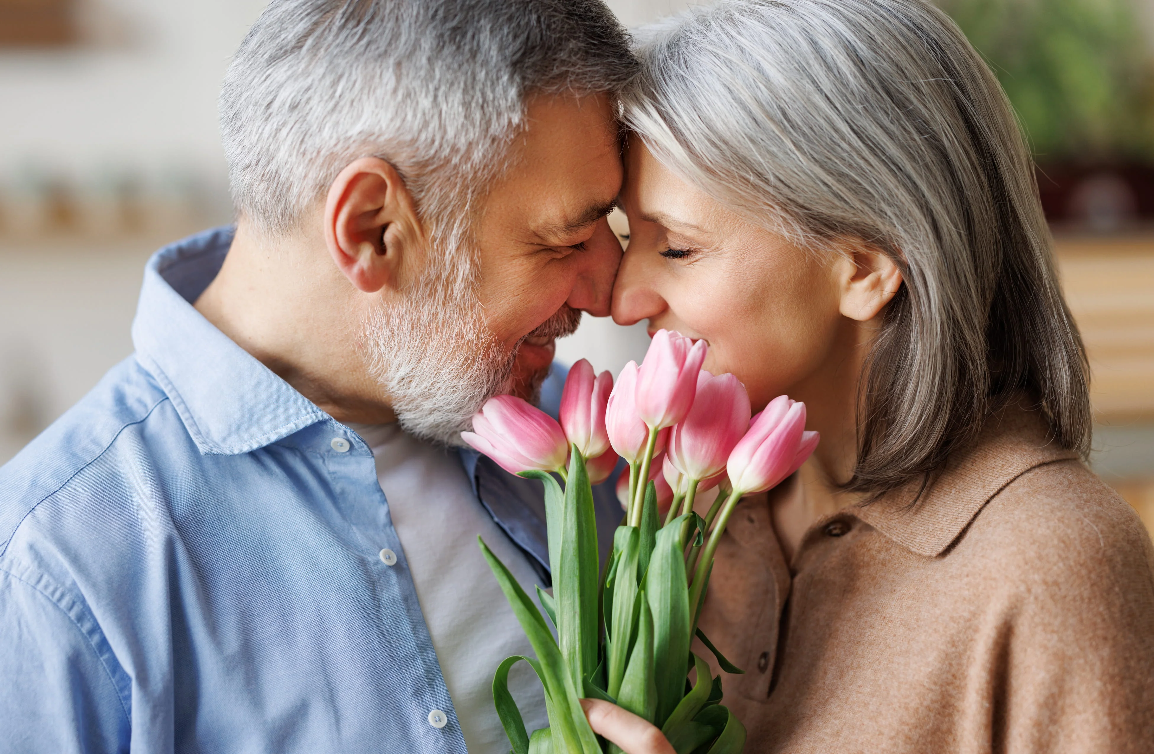 Happy mature couple sharing a romantic moment while holding pink tulips